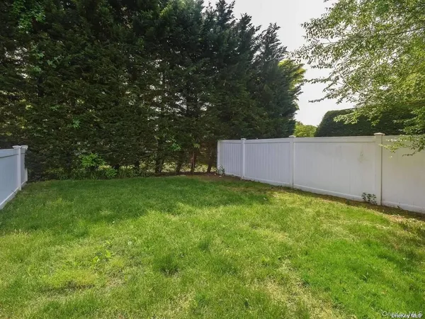 a backyard of a house with lots of plants and large tree