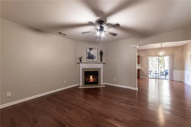 a view of an empty room with wooden floor fireplace and a window