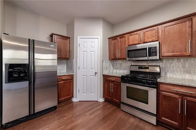 a view of a refrigerator in kitchen and an empty room