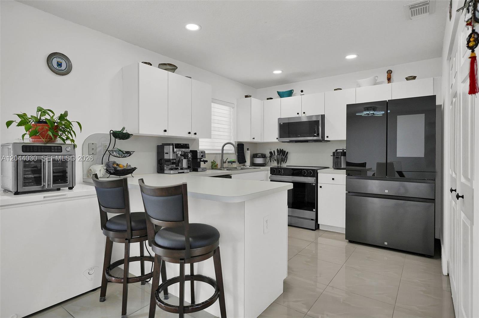 12551 Southwest 223rd Street Miami, FL 33170 - Photo 9 of 35 a kitchen with white cabinets and stainless steel appliances