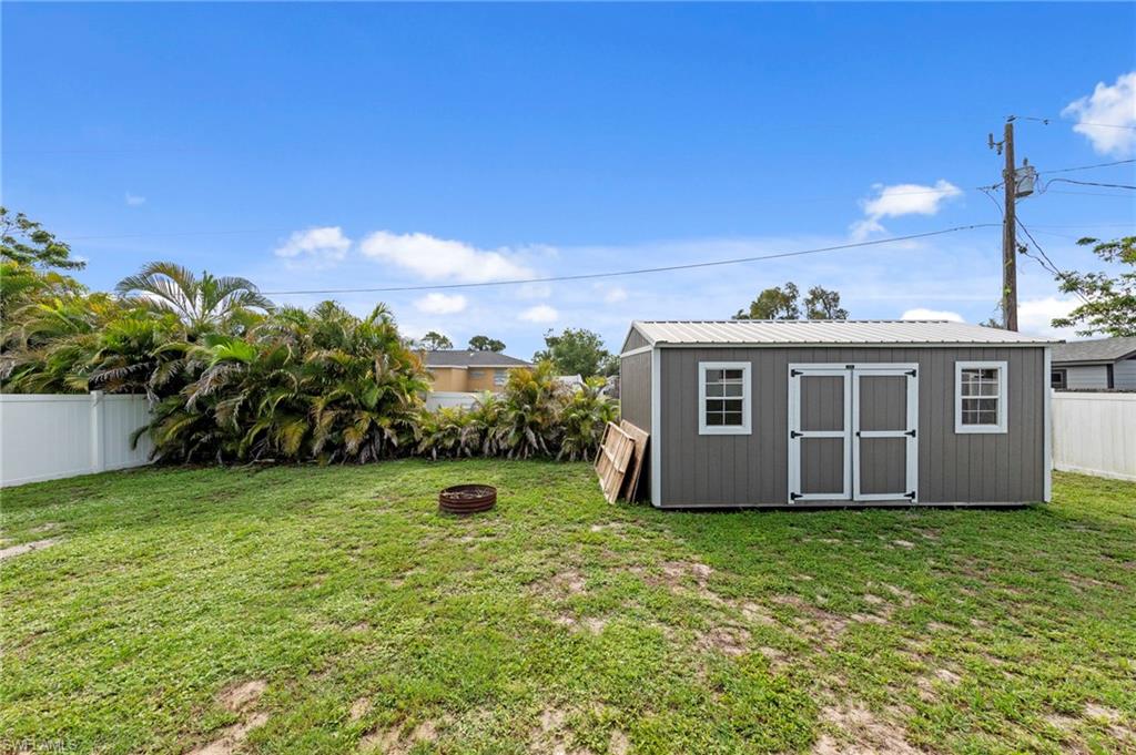 18435 Heather Road Fort Myers, FL 33967 - Photo 26 of 34 Spacious backyard featuring a gray storage shed with white trim, a metal roof, double entry doors, and two windows