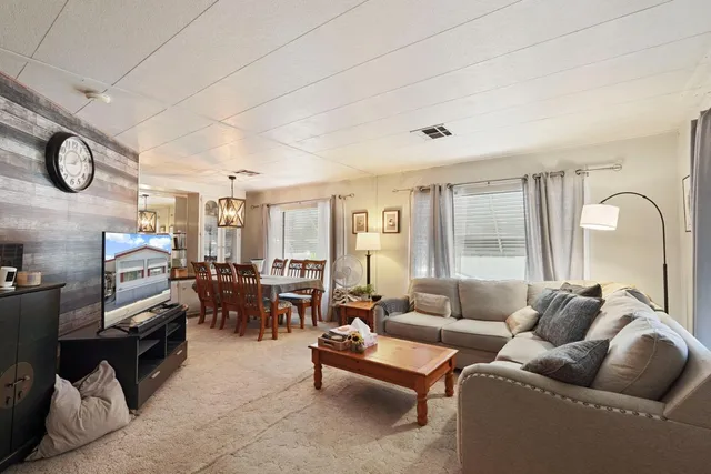 a living room with furniture ceiling fan and a large window