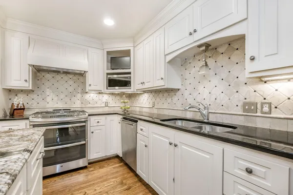 a kitchen with stainless steel appliances granite countertop a sink and a refrigerator
