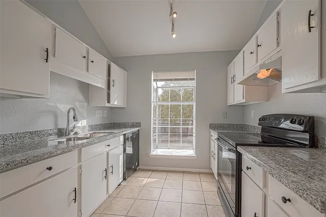 a kitchen with granite countertop a sink stove and cabinets