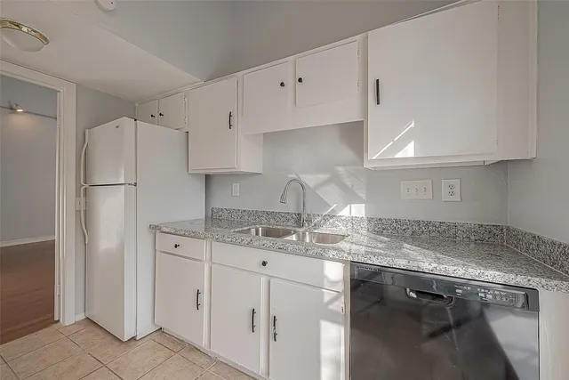 a kitchen with granite countertop white cabinets and stainless steel appliances