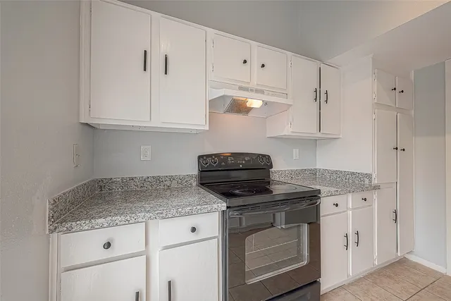 a kitchen with granite countertop a sink stove and cabinets