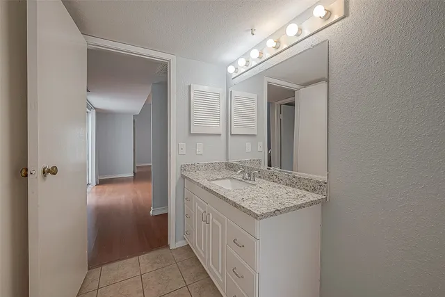 a bathroom with a granite countertop sink and a mirror