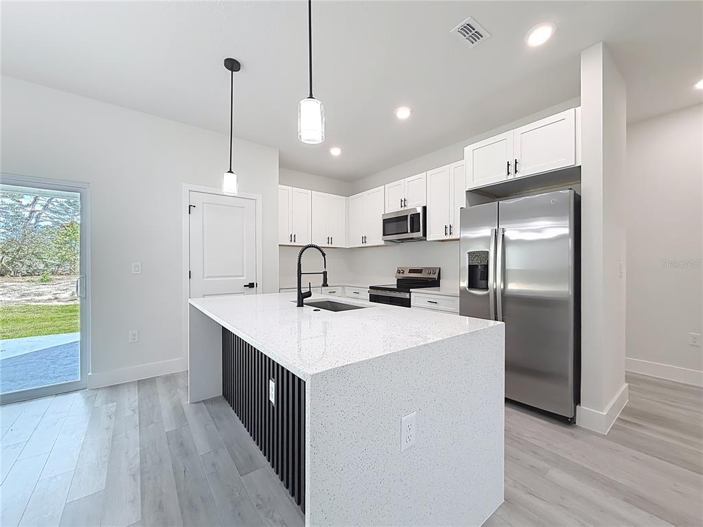 8425 North Legacy Loop Citrus Springs, FL 34433 - Photo 11 of 51 a kitchen with stainless steel appliances a sink a stove a refrigerator and island with wooden floor