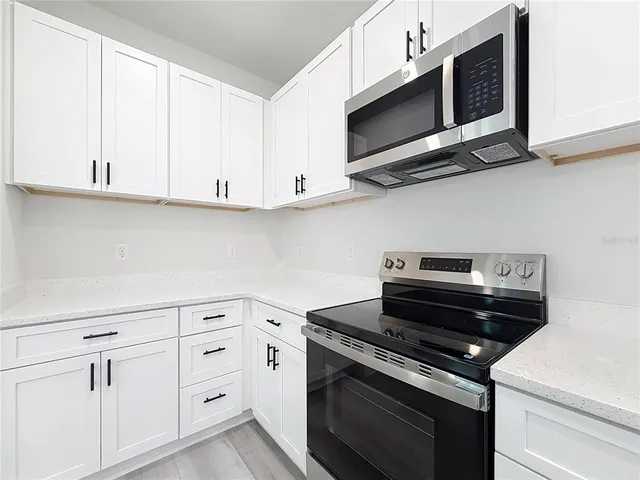 a kitchen with white cabinets and appliances