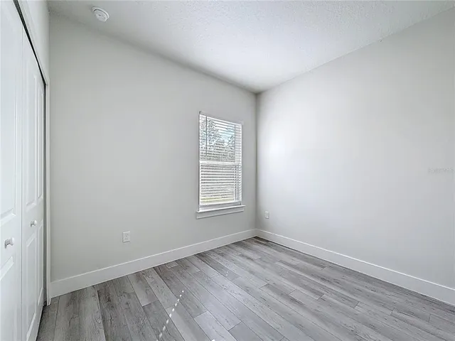 an empty room with wooden floor and window