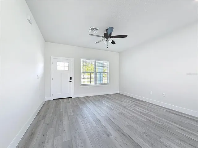 a view of empty room with wooden floor and fan