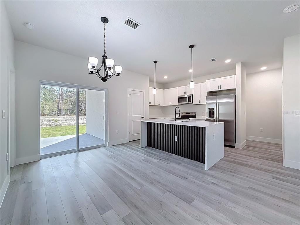 8425 North Legacy Loop Citrus Springs, FL 34433 - Photo 10 of 51 a large kitchen with stainless steel appliances granite countertop a stove a sink dishwasher a refrigerator and a fireplace with wooden floor