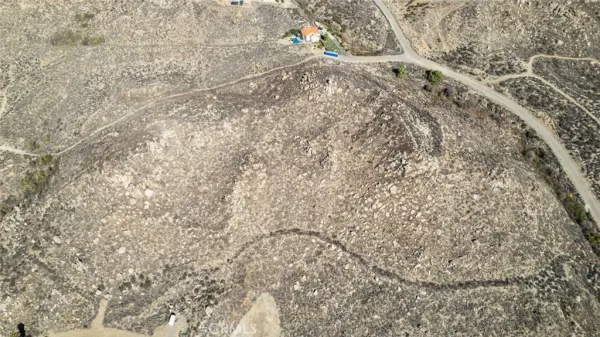 a view of a dry yard with mountains and green space
