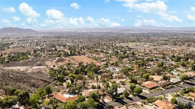 a view of a dry yard with trees in the background