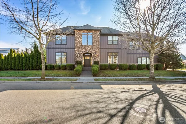 a view of a big house with a big yard and large trees