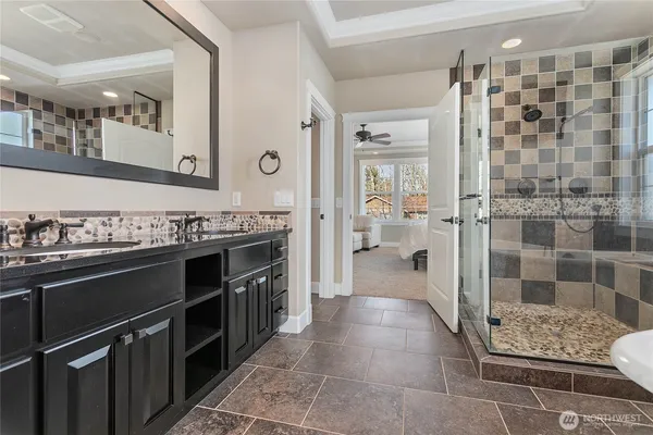 a bathroom with a granite countertop sink a mirror and shower