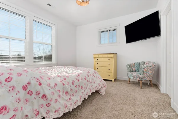 a bedroom with a bed a flat screen tv and a chair