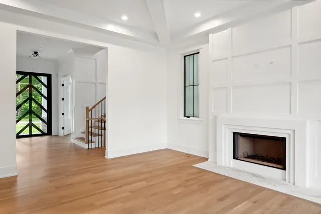 a view of an empty room with wooden floor fireplace and a window