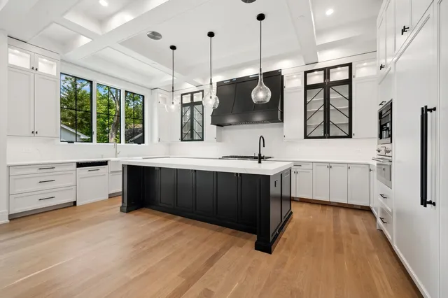 a kitchen with stainless steel appliances kitchen island granite countertop a sink a stove and a wooden floors