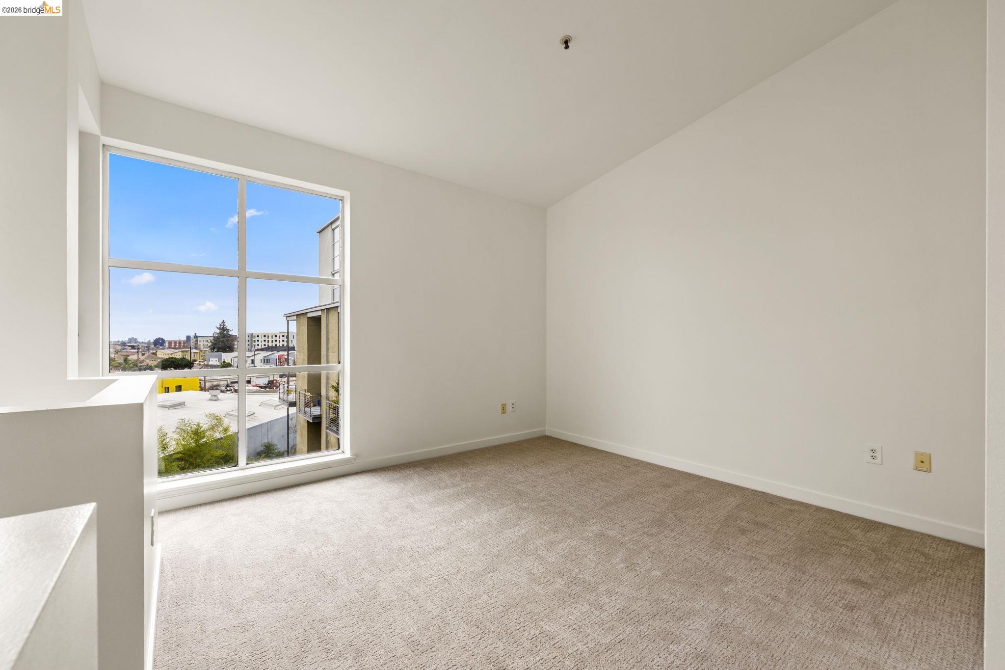 1007 41st Street, Unit 333 Oakland, CA 94608 - Photo 30 of 49 Empty room featuring light colored carpet and vaulted ceiling
