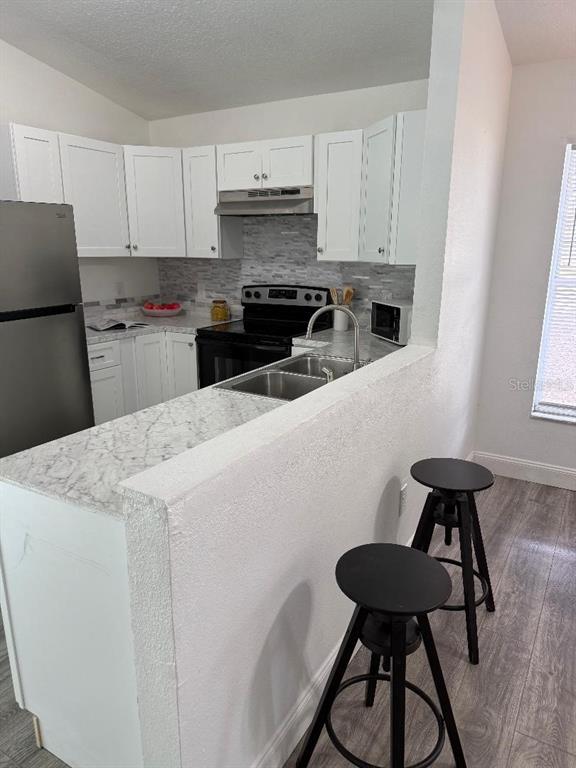 1502 West 16th Street Sanford, FL 32771 - Photo 6 of 12 a kitchen with stainless steel appliances kitchen island a table chairs in it white cabinets and a wooden floor
