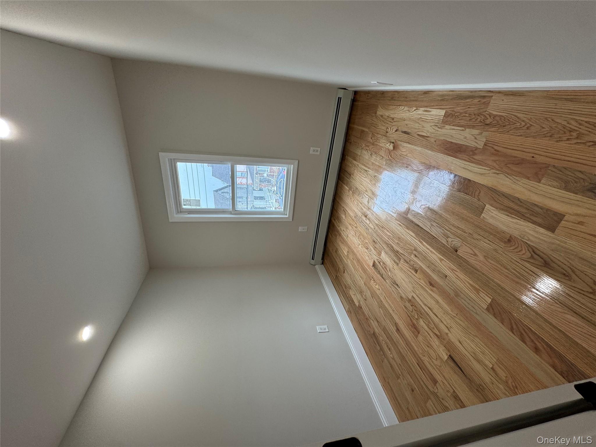 194-45 Murdock Avenue Queens, NY 11412 - Photo 12 of 23 an empty room with wooden floor and windows