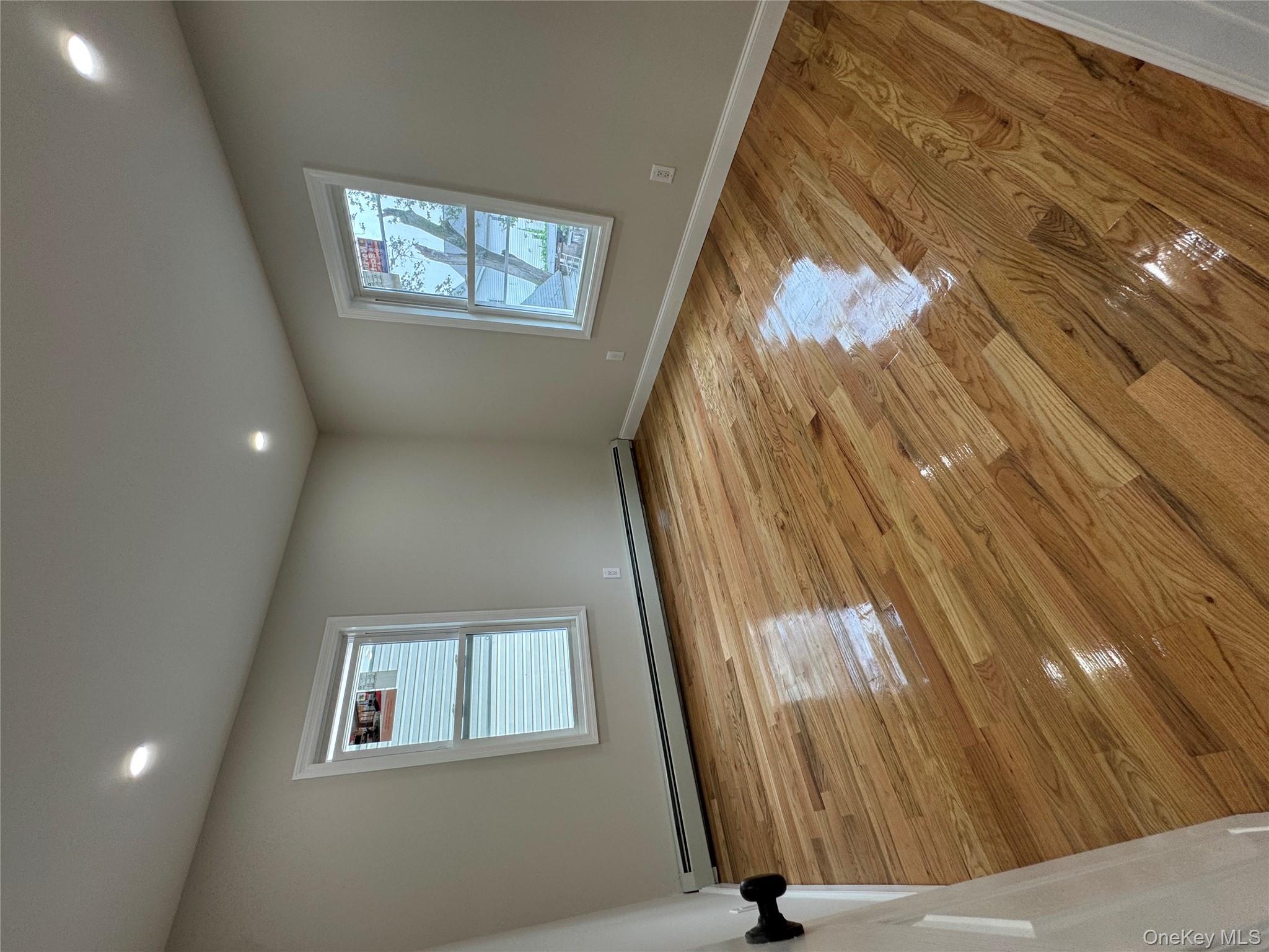 194-45 Murdock Avenue Queens, NY 11412 - Photo 13 of 23 a view of an empty room with wooden floor and a window