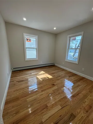 a view of empty room with window and wooden floor