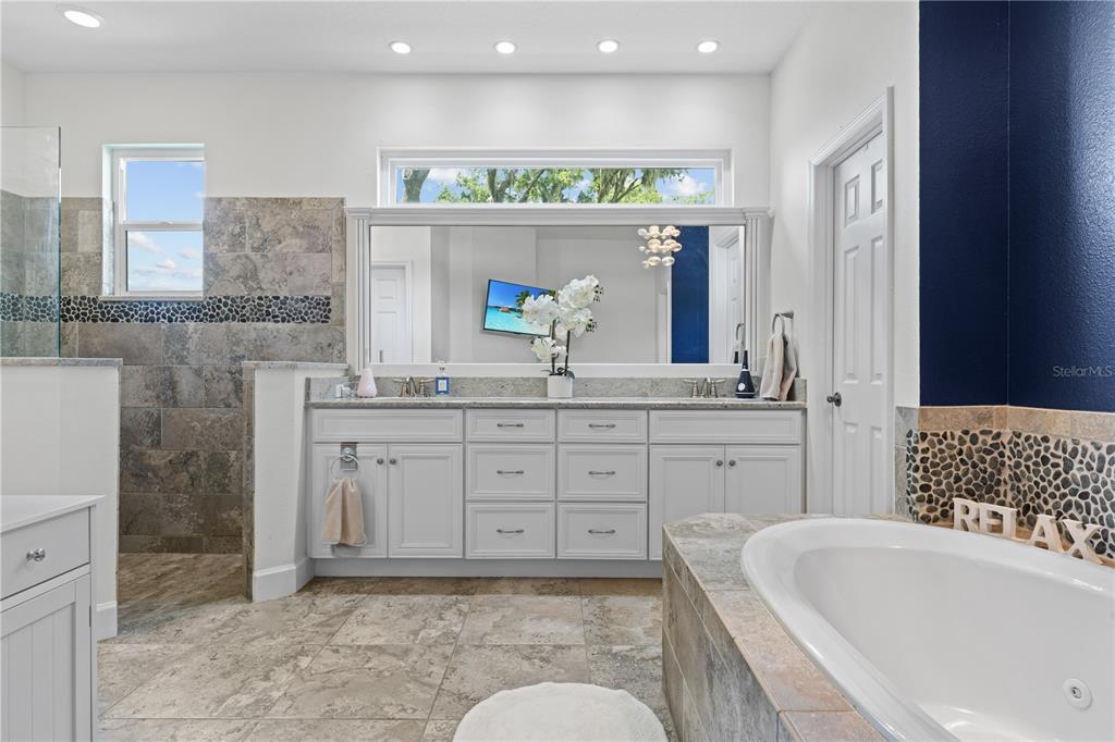 16948 Deer Island Road Tavares, FL 32778 - Photo 22 of 67 a spacious bathroom with a granite countertop sink mirror and bathtub