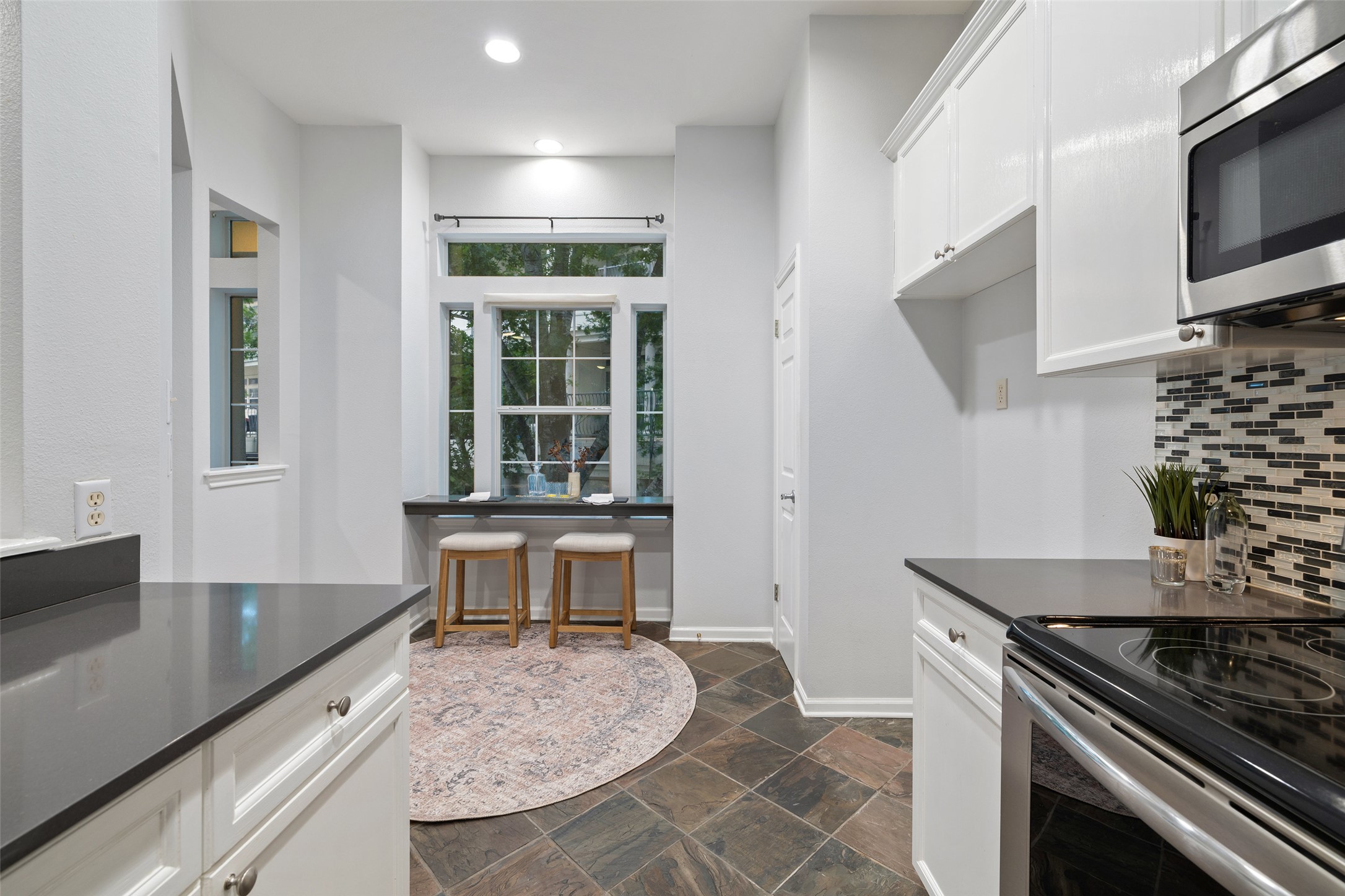 2918 Ranch To Market Road 620, Unit O282 Austin, TX 78734 - Photo 12 of 40 Kitchen featuring stainless steel appliances, stone tile flooring, dark countertops, and tasteful backsplash