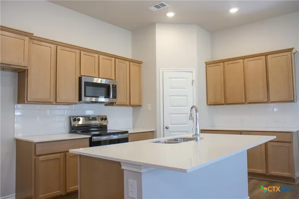 a kitchen with stainless steel appliances a sink a stove a microwave a sink and cabinets