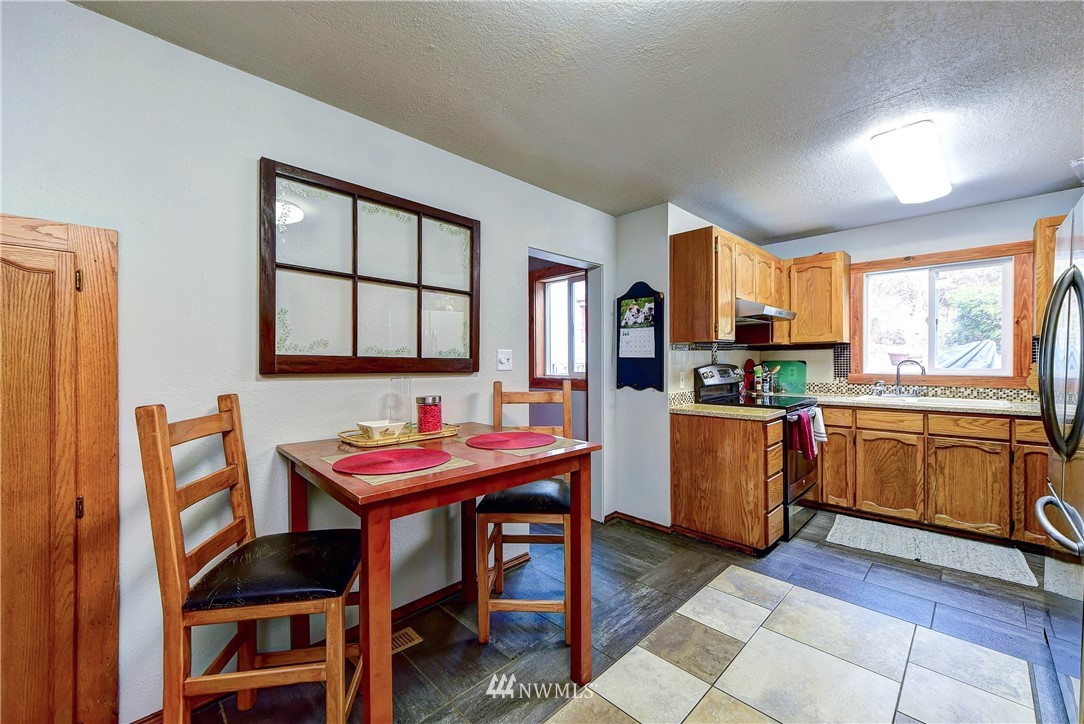 3625 Newberg Road Snohomish, WA 98290 - Photo 10 of 25 a kitchen with stainless steel appliances kitchen island granite countertop a table chairs in it and wooden floors