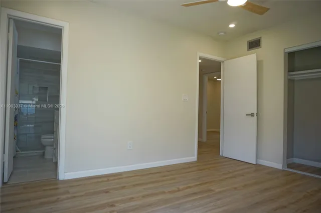 a view of an empty room with wooden floor and a bathroom