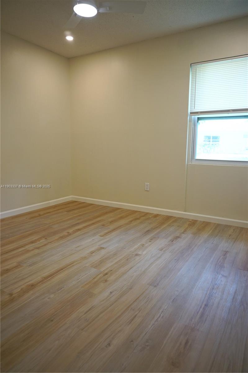 971 Fulton Lane Northeast Palm Bay, FL 32905 - Photo 23 of 29 an empty room with wooden floor and windows