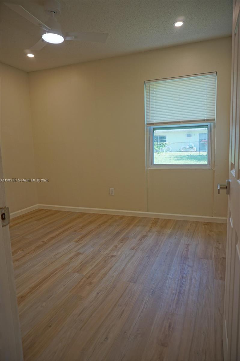 971 Fulton Lane Northeast Palm Bay, FL 32905 - Photo 27 of 29 an empty room with wooden floor and windows