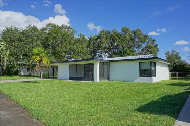 a front view of house with yard and trees in the background