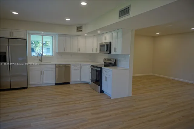 a large kitchen with stainless steel appliances granite countertop a stove a sink and a refrigerator