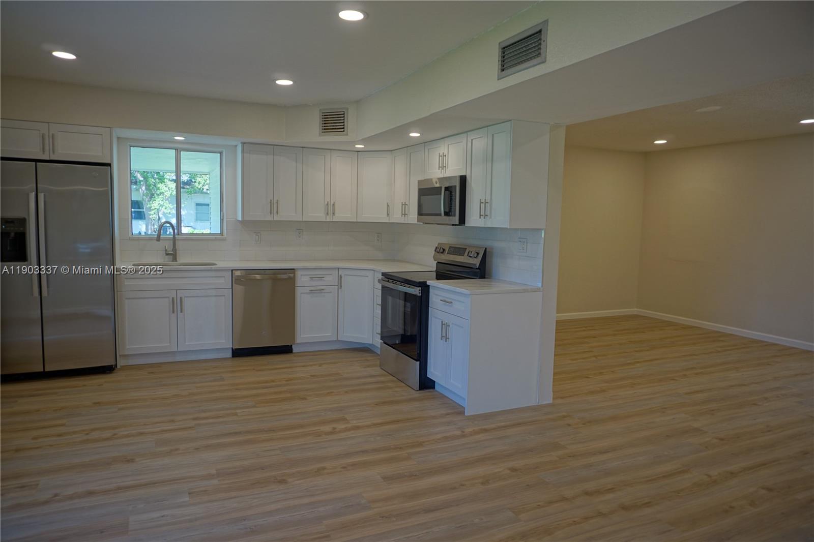 971 Fulton Lane Northeast Palm Bay, FL 32905 - Photo 6 of 29 a large kitchen with stainless steel appliances granite countertop a stove a sink and a refrigerator
