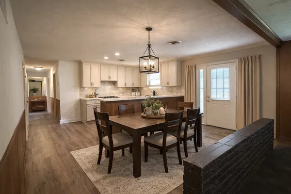 a dining room with stainless steel appliances granite countertop wooden floor a dining table and chairs