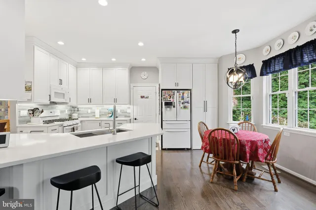 a kitchen with stainless steel appliances kitchen island granite countertop a dining table chairs and white cabinets