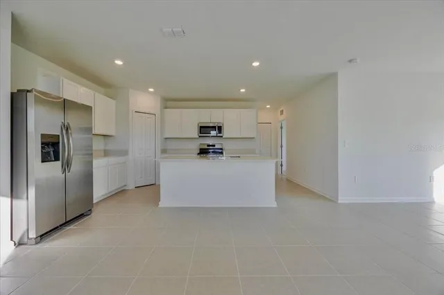 a large kitchen with stainless steel appliances a refrigerator and a microwave