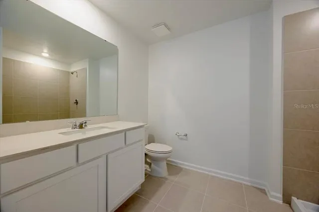 a bathroom with a granite countertop sink a toilet and a mirror