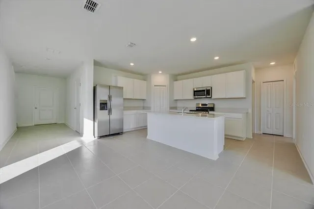 a view of kitchen with refrigerator and white cabinets
