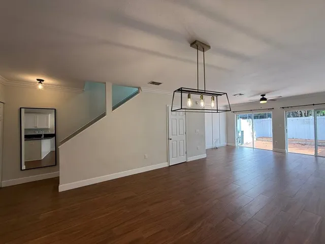 a view of an empty room with wooden floor and windows