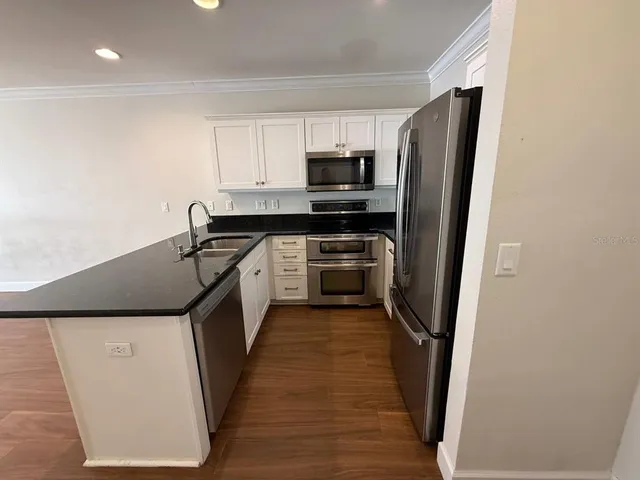 a kitchen with stainless steel appliances a refrigerator a sink and white cabinets
