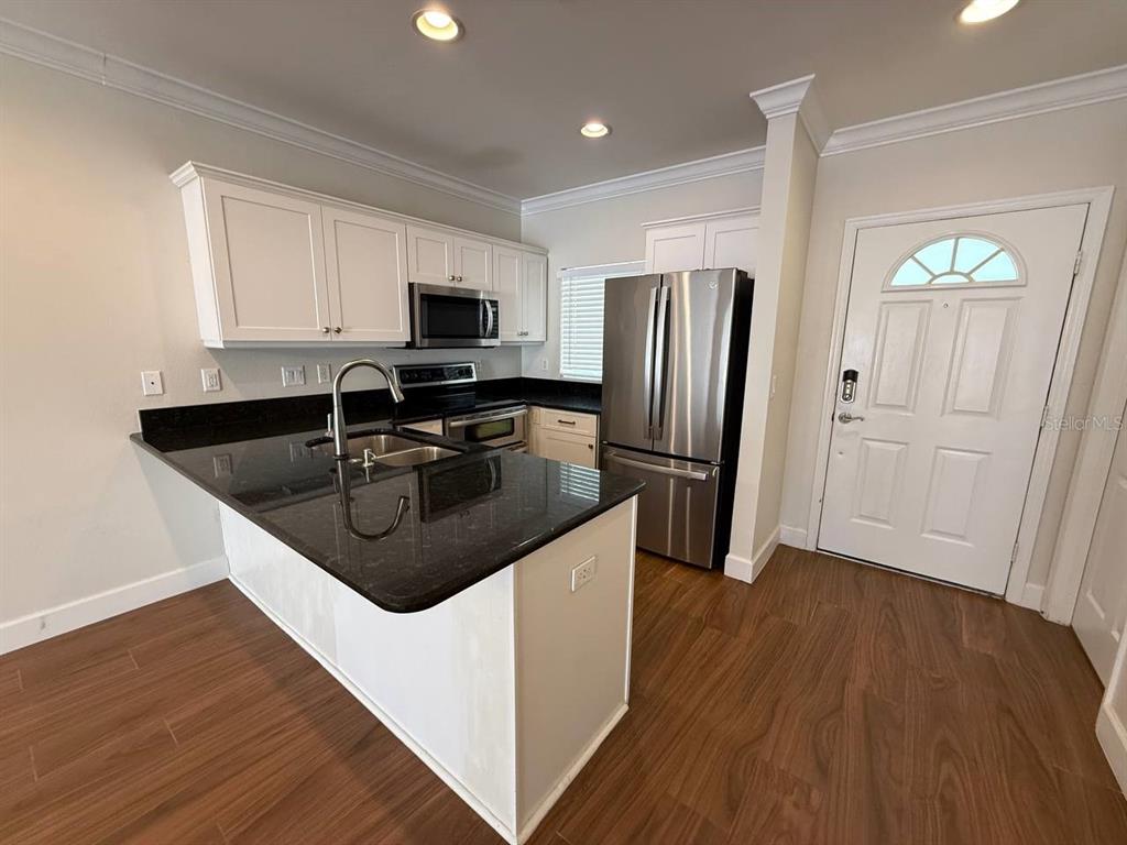 2513 West Kansas Avenue, Unit B Tampa, FL 33629 - Photo 6 of 27 a kitchen with stainless steel appliances granite countertop a refrigerator a sink a stove a microwave and wooden floors