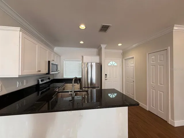 a kitchen with stainless steel appliances granite countertop a sink a stove and a refrigerator