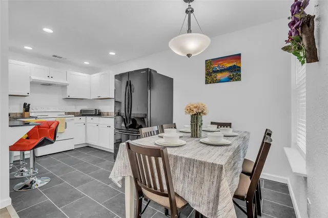 a kitchen with stainless steel appliances granite countertop a stove a sink a microwave a refrigerator and chairs