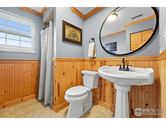 a bathroom with a sink a mirror a toilet and a window