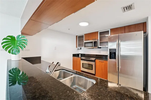 a kitchen with stainless steel appliances a sink a counter top space cabinets and a potted plant